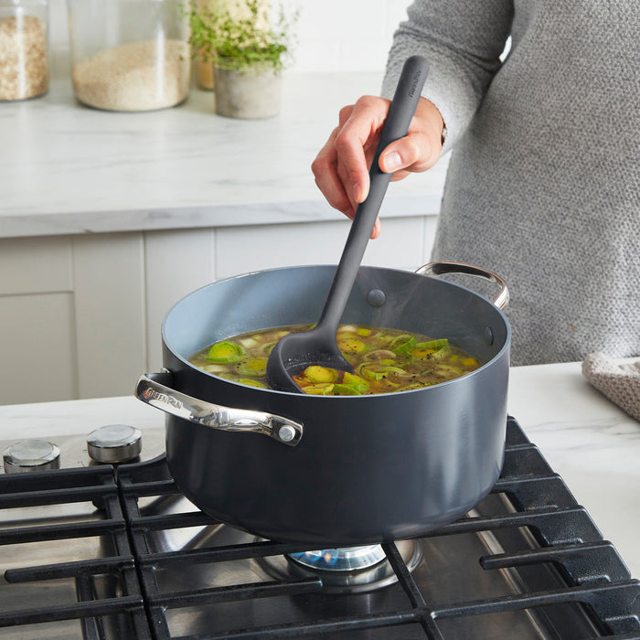 Person using a silicone ladle to scoop soup out of a stockpot