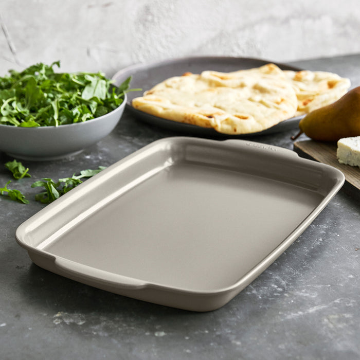 Taupe ceramic nonstick quarter sheet pan on a countertop, with flatbread and cheese beside it.