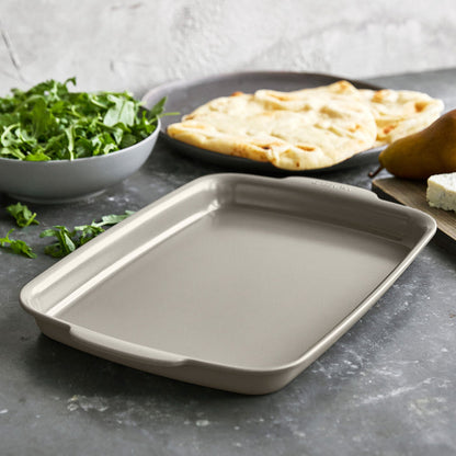 Taupe ceramic nonstick quarter sheet pan on a countertop, with flatbread and cheese beside it.