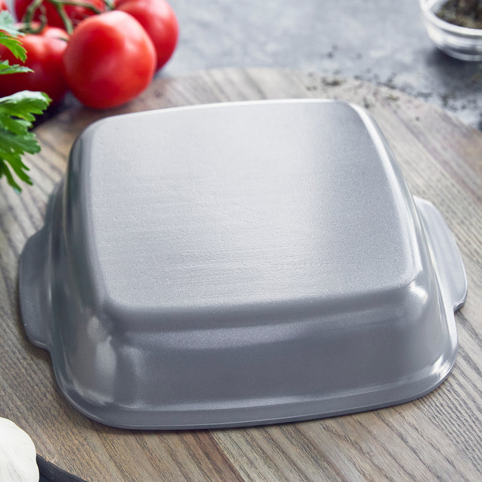Gray ceramic nonstick 2-piece cake pan set on wood surface with tomatoes and herbs nearby.
