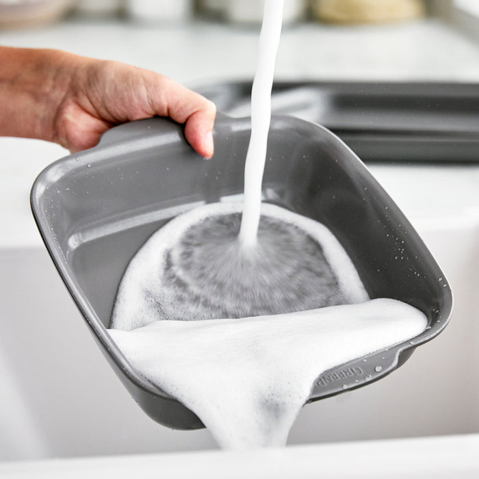 Gray ceramic nonstick 2-piece cake pan set held over a white sink with water overflowing.