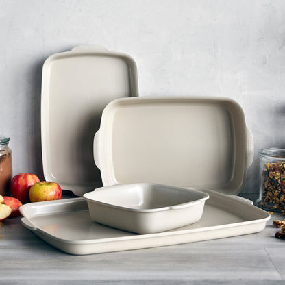 Taupe ceramic nonstick ovenware 4-piece set on a kitchen counter with apples and jars nearby.