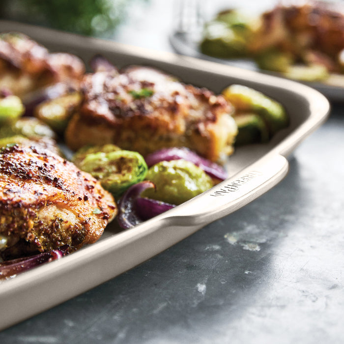Roasted chicken and vegetables in taupe ceramic nonstick bakeware set on a gray countertop.