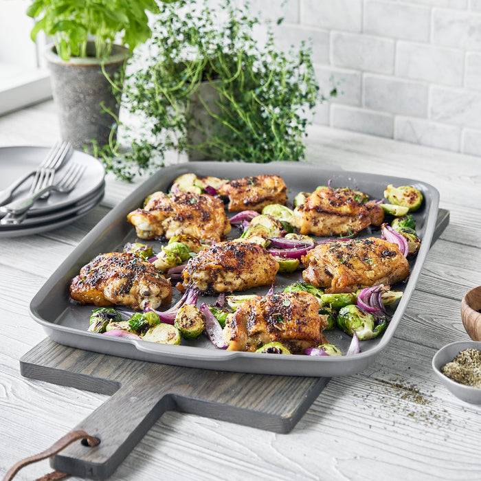 Gray ceramic nonstick ovenware set with five pieces, shown with roasted chicken, Brussels sprouts, and onions.