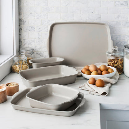 Taupe ceramic nonstick 5-piece bakeware set on a kitchen counter with visible baking ingredients.