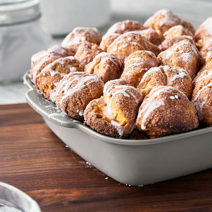 Monkey bread with white icing in a taupe ceramic square baker, 8x8, by Premiere Ovenware.