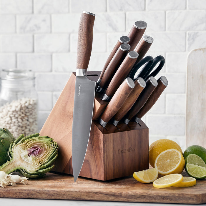 12-piece titanium cutlery set with walnut handles on a kitchen counter next to sliced citrus fruits.