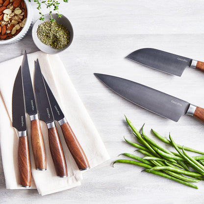 12-piece titanium cutlery set with walnut handles on a napkin, surrounded by herbs, almonds, and green beans.