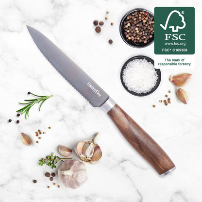 Serrated utility knife with walnut handle on marble, surrounded by garlic, herbs, spices; FSC logo visible.