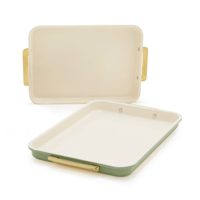 Set of two sage green quarter sheet pans with cream interiors and gold handles.