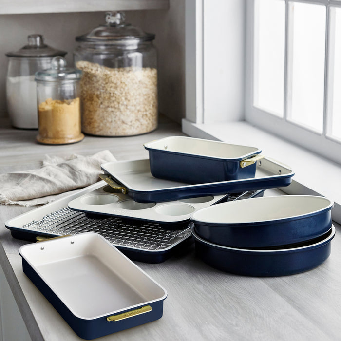 Blue and white 8-piece bakeware set on a kitchen counter near glass jars and a window.