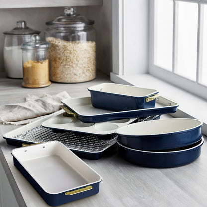 Blue and white 8-piece bakeware set on a kitchen counter near glass jars and a window.