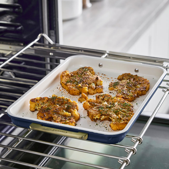 Four cauliflower steaks on a dark Reserve Bakeware tray, part of the 8-piece set, on a modern kitchen counter.
