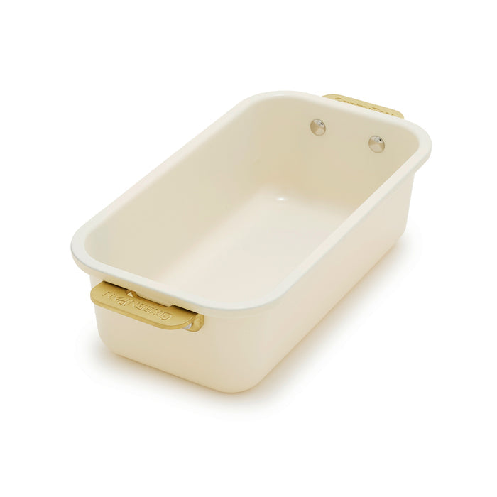 Cream loaf pan with gold handles on a white background