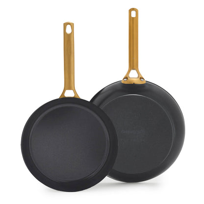 Two black frying pans with gold handles on a white background