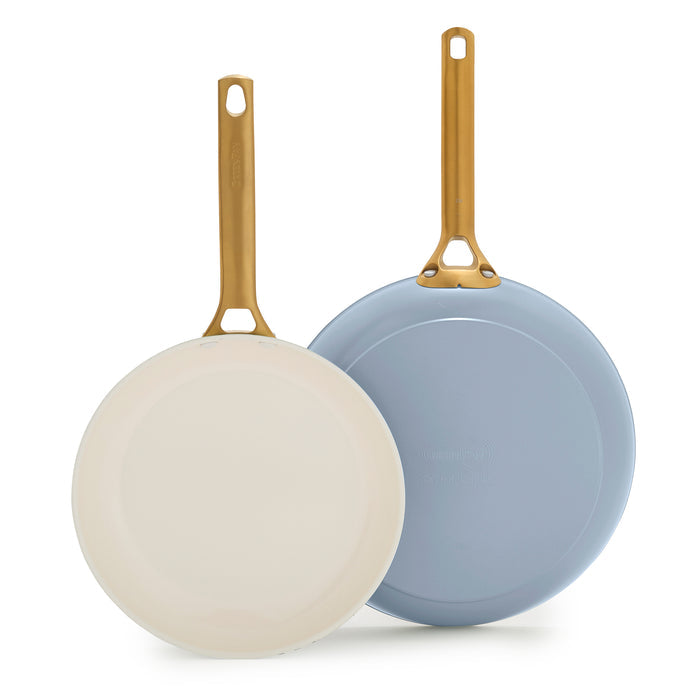 Two light blue frying pans with gold handles on a white background