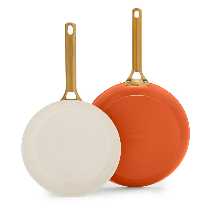 Two dark orange frying pans with gold handles on a white background.