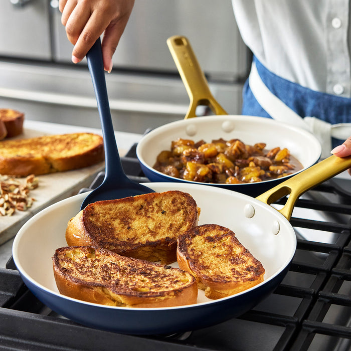 Person cooking French toast in a dark blue frypan with a spatula