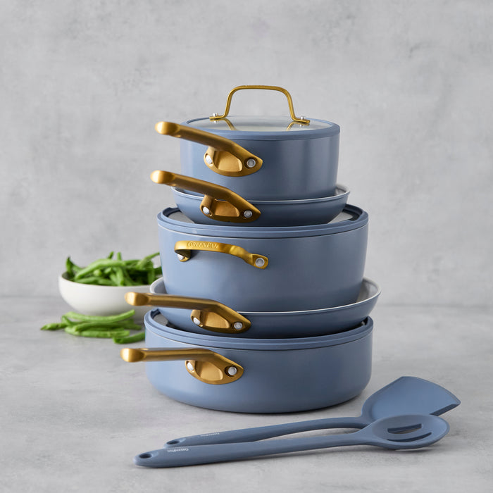 Stack of blue cookware with gold handles on a gray background