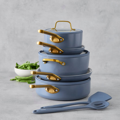 Stack of blue cookware with gold handles on a gray background