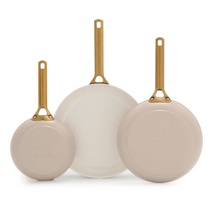 Set of three taupe frying pans with gold handles on a white background