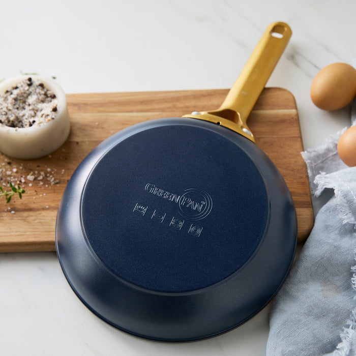 Dark blue frying pan with a gold handle on a wooden cutting board