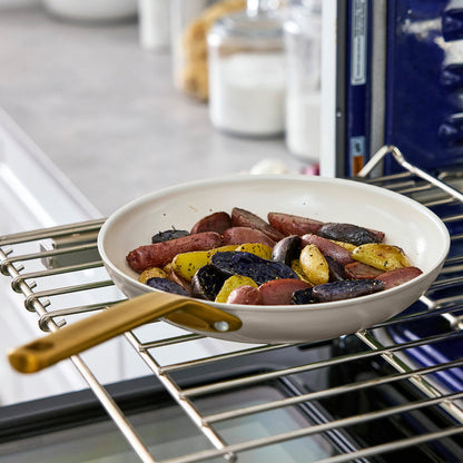 Taupe gray frying pan with sausages and potatoes in an oven
