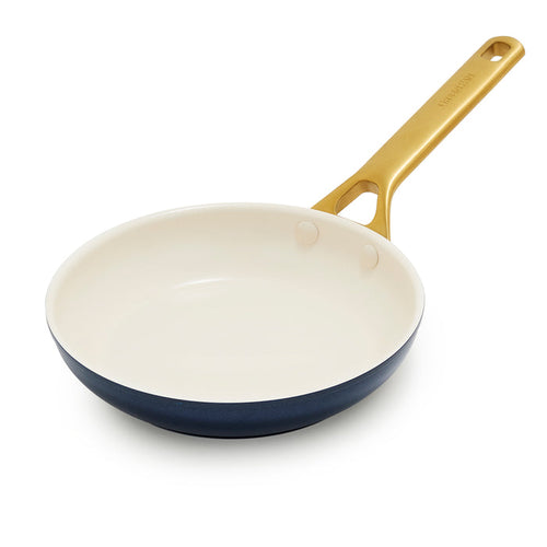 Dark blue frying pan with a gold handle on a white background
