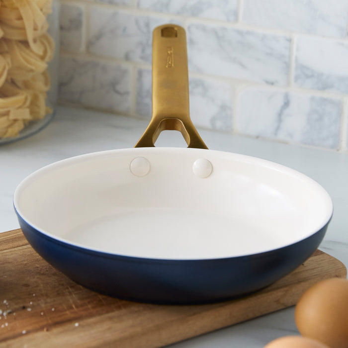 Dark blue frying pan with a cream interior on a wooden cutting board.