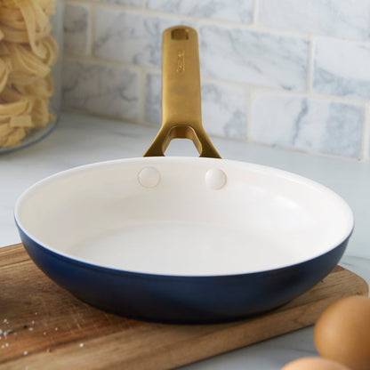Dark blue frying pan with a cream interior on a wooden cutting board.