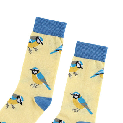 A pair of light yellow crew socks with a blue and yellow bird pattern, featuring solid blue ribbed cuffs and heels, displayed on a white background.