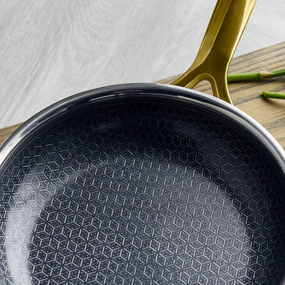 Gold ceramic nonstick frypan set on a wooden surface with asparagus beside it.