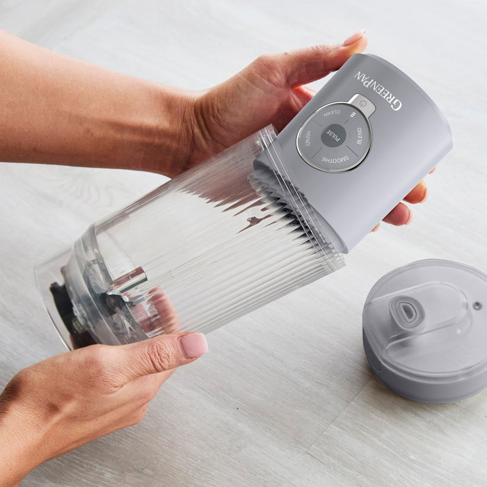 Hand holding a portable blender on a light surface