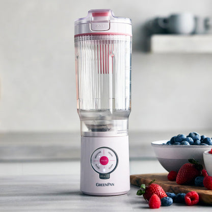 Portable blender with a clear container on a kitchen counter with berries