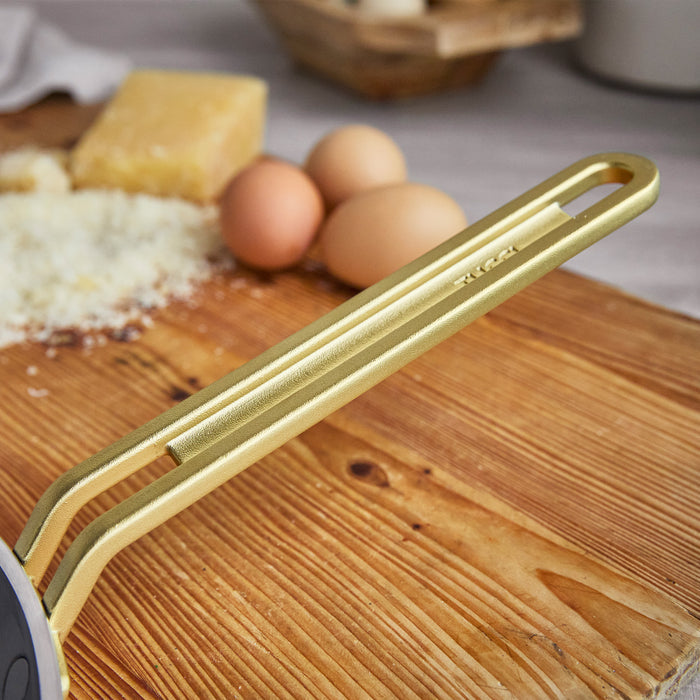 Ceramic nonstick 10-inch pan in orange set on wood, with eggs, cheese, and a grater in the background.