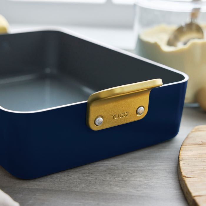 Marino Blue ceramic lasagna pan with gold handle on a kitchen counter.