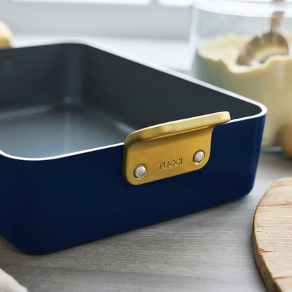 Marino Blue ceramic lasagna pan with gold handle on a kitchen counter.