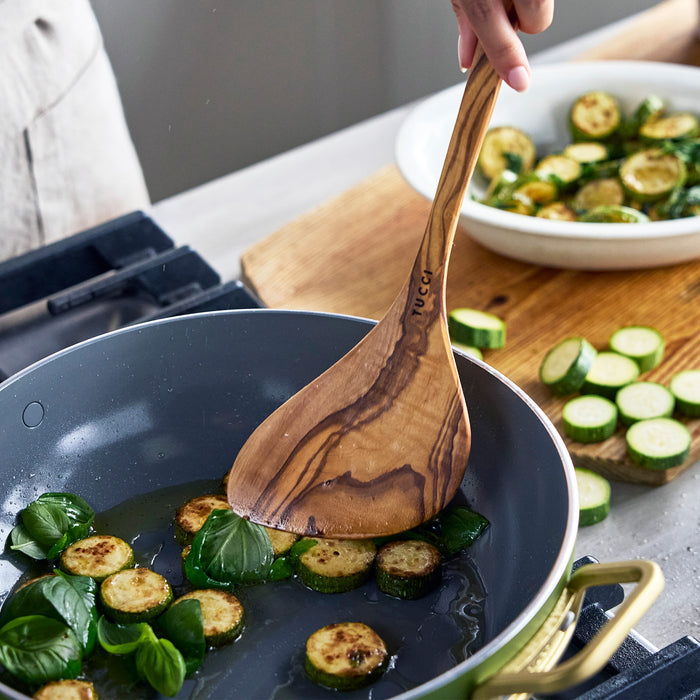 Cooking zucchini in a pan with a wooden spoon
