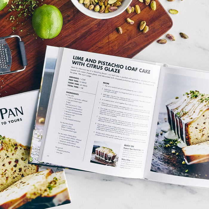 Open cookbook on a kitchen counter to lime and pistachio loaf cake recipes, with some ingredients next to it.