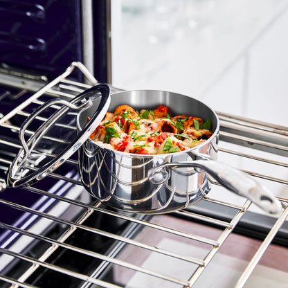Stainless steel saucepan with lid, uncoated, 1.6-quart size, on an oven rack with food inside.